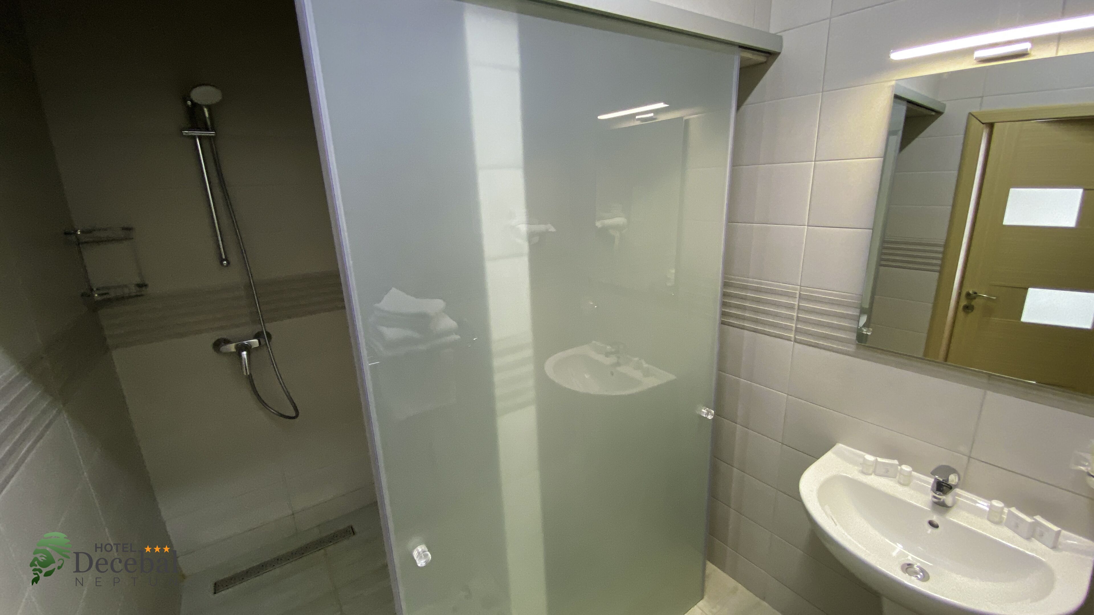 A modern bathroom with a glass-enclosed shower, a sink, and a mirror.
