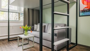 Un salon moderne avec un canapé gris, une table basse blanche et un vase en verre contenant des fleurs.