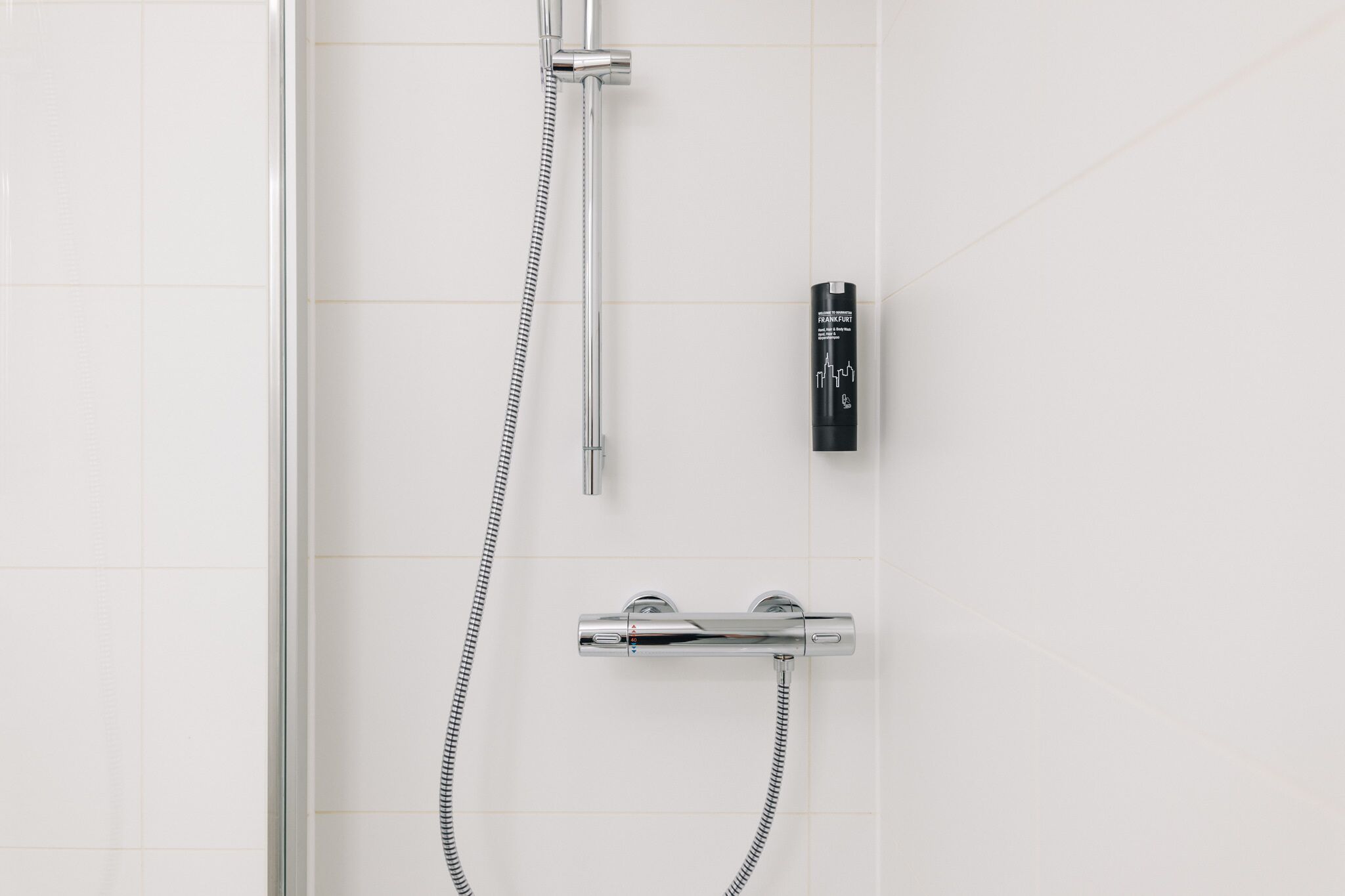 Una ducha con cabezal de ducha de mano, un accesorio de ducha manual y un grifo empotrado.