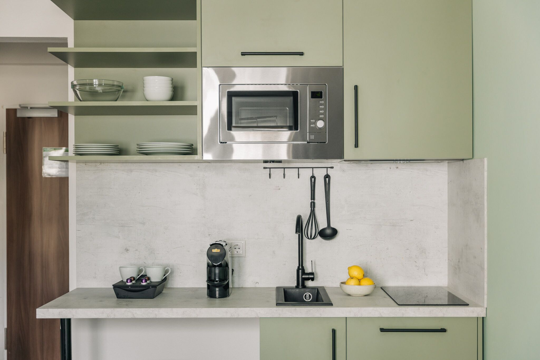 A modern kitchen with a built-in microwave, a coffee maker, and a kettle on the countertop.