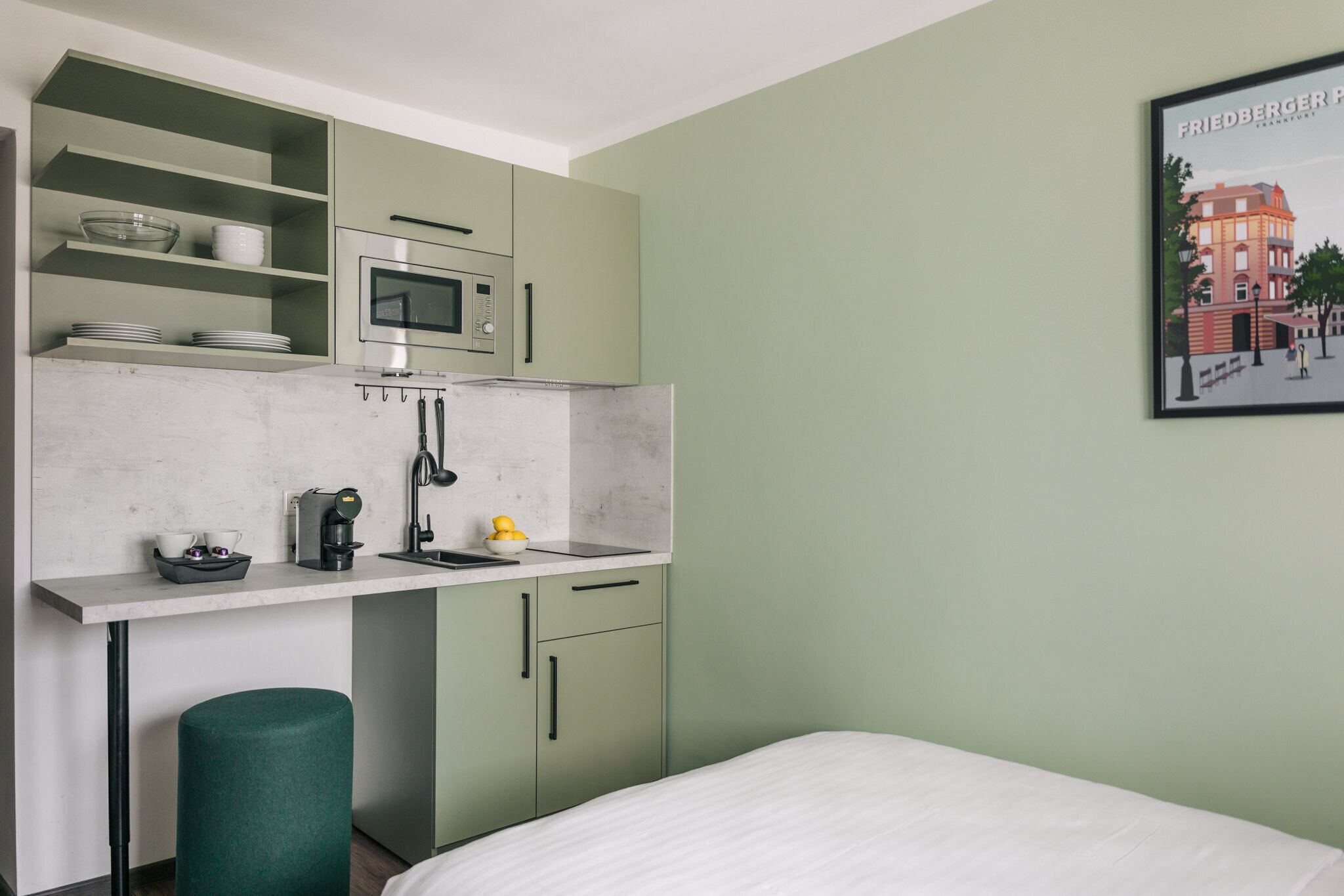 Una kitchenette compacta con microondas, cafetera y un lavamanos pequeño.
