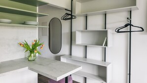 Une chambre moderne avec une table en marbre, un vase de fleurs et des étagères blanches équipées de cintres noirs.