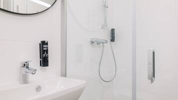 A modern bathroom with a white sink, a handheld showerhead, and a glass-enclosed shower.