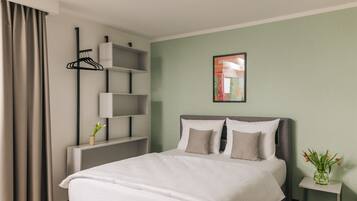 A neatly arranged hotel room with a bed, bedside tables, a wall-mounted shelf, and a framed picture.