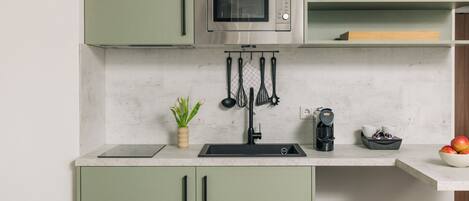 A kitchen with a built-in microwave, a sink, and a coffee maker.