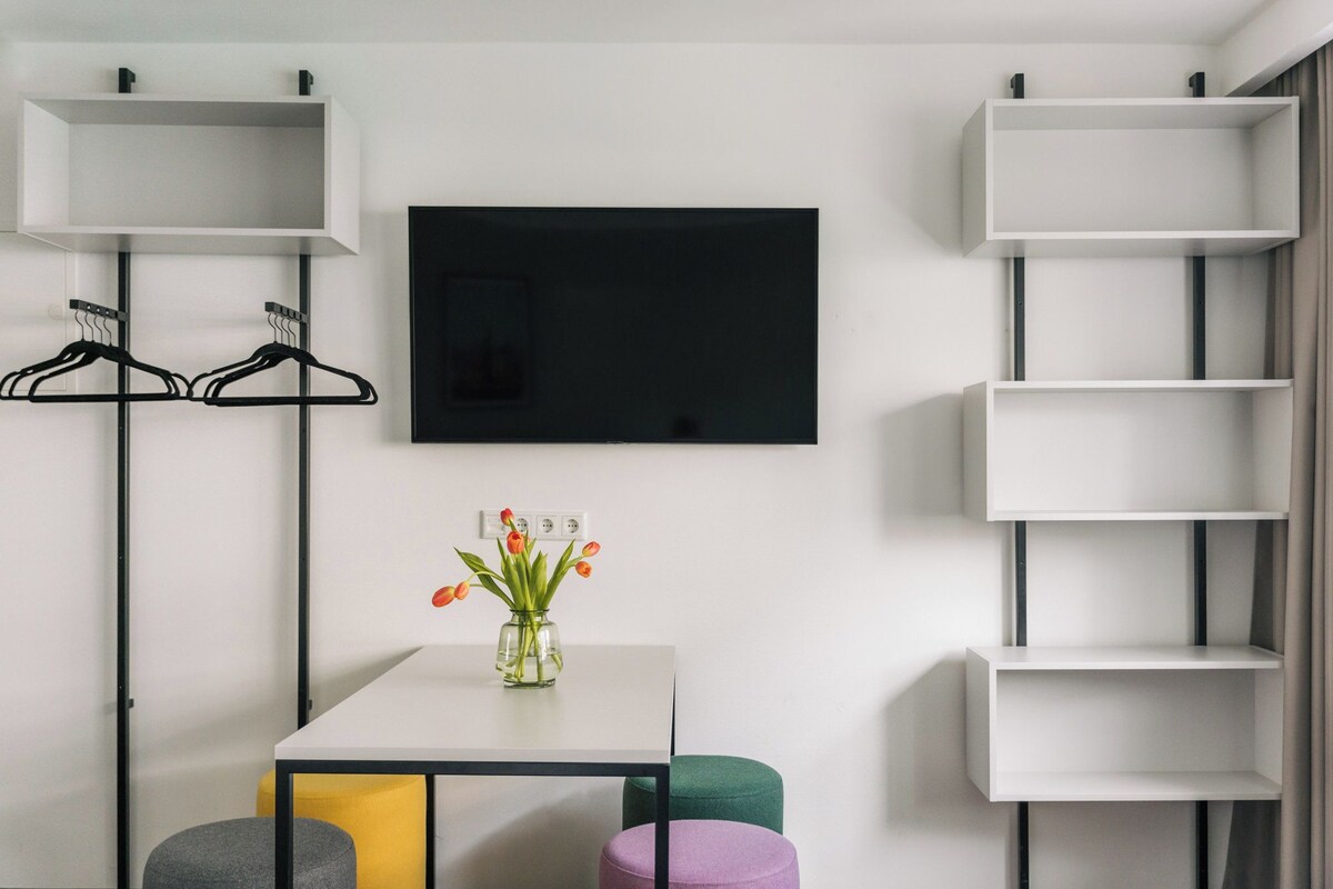 Une chambre moderne avec une table blanche, un téléviseur à écran plat et des étagères intégrées.