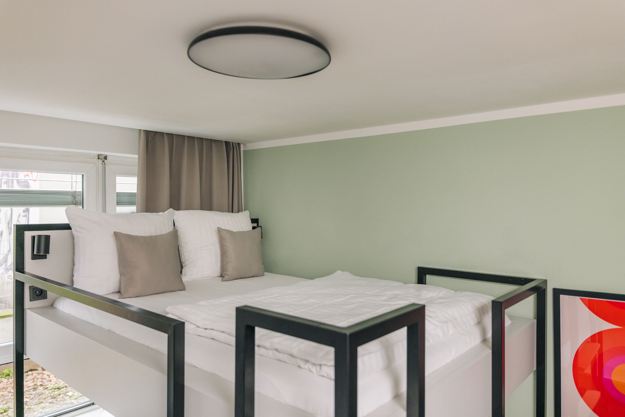 Een moderne slaapkamer met een stapelbed, een nachtkastje en een raam met gordijnen.