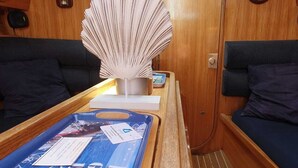 Ein Interieur einer Holzhütte mit einem Holztisch, einem Ventilator, einer Fernbedienung und einem Fenster mit Blick ins Freie.