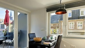 A dining area with a table set for two, a black chair, a wooden bowl, and a vase with flowers. - Holiday on the Moselle in the Weinberg holiday apartment in Zell (Moselle) (Zell (Mosel))