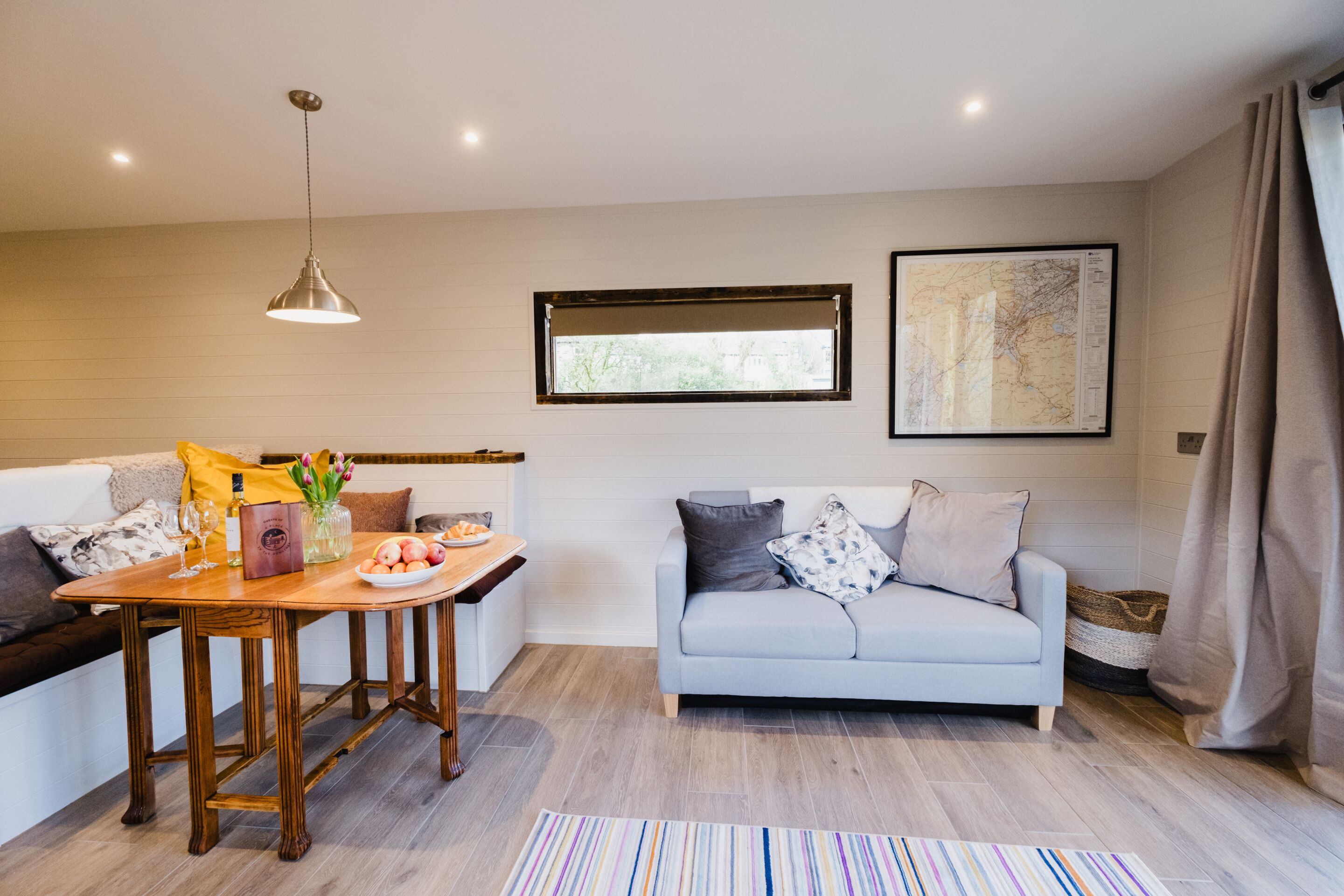 A modern living room with a dining area, a sofa, a coffee table, and a map on the wall.