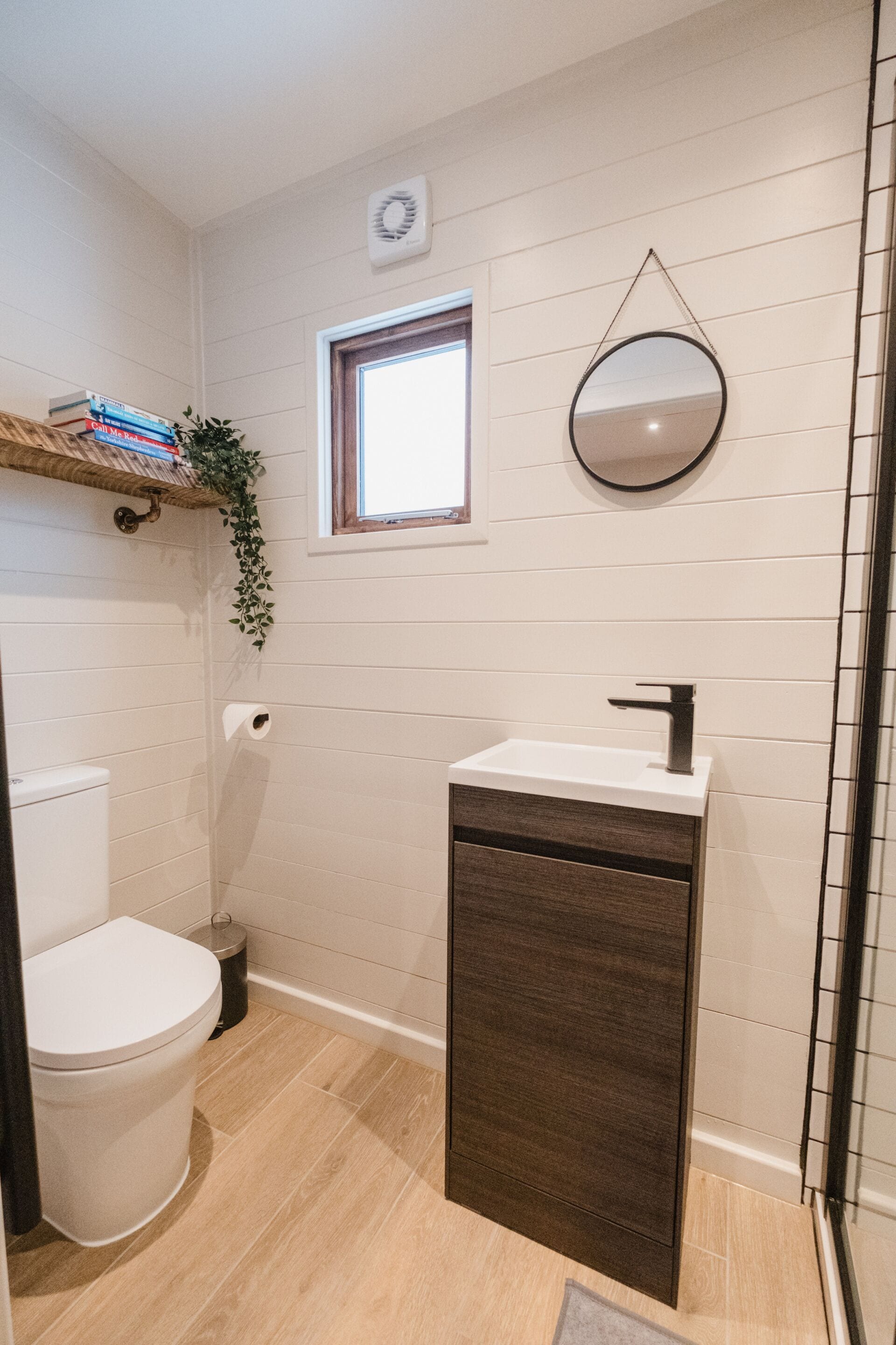 A bathroom with a toilet, a sink, a mirror, and a window.