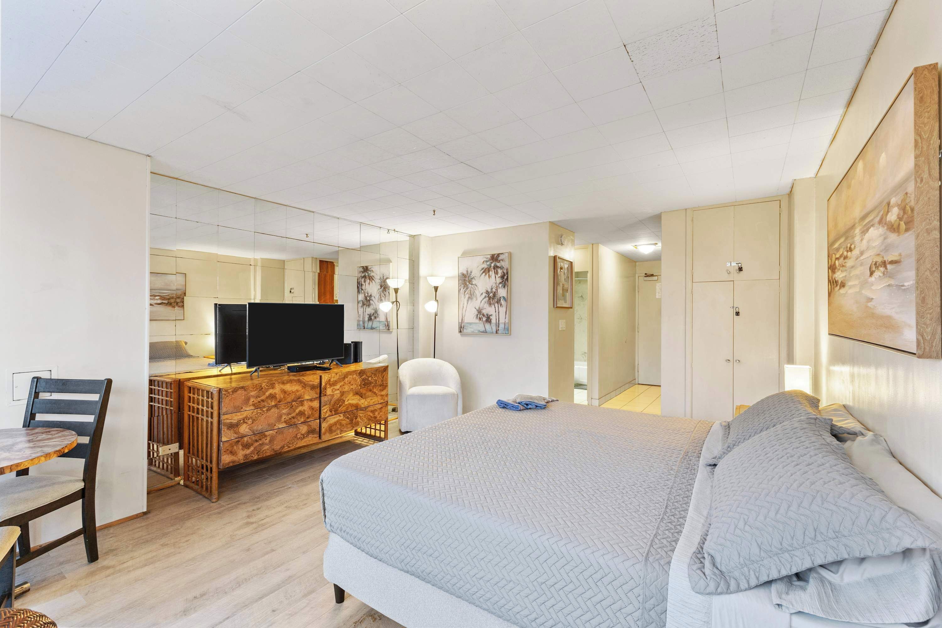 Une chambre d’hôtel comprenant un lit, un bureau avec une télévision, une chaise et une armoire.