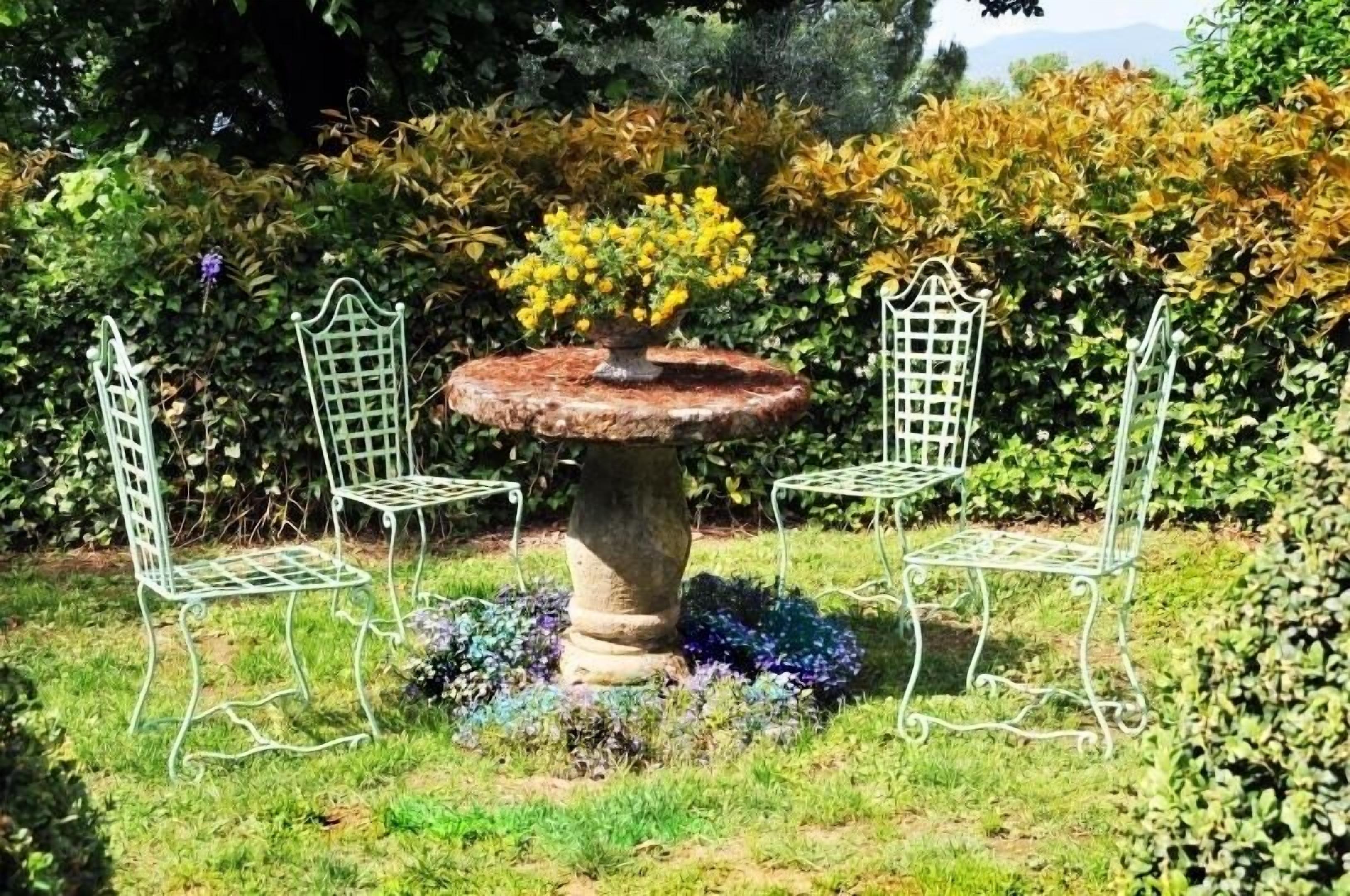 A garden with a stone table and two metal chairs.