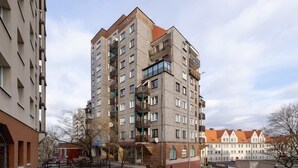 Un edificio residencial de varios pisos con balcones, fachada de ladrillo y tejado rojo.