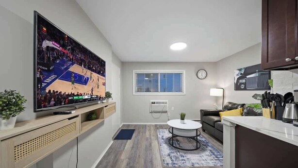 A modern kitchen with a flat-screen TV, a dining area with a round table, and a living room with a sofa. - Modern 1BD Apartment Near Ferndale (Hazel Park)