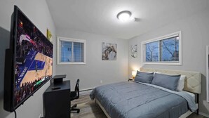 A bedroom with a bed, a TV mounted on the wall, a desk, and a chair. - Modern 1BD Apartment Near Ferndale (Hazel Park)