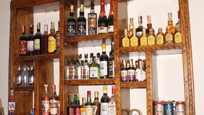 A wooden liquor cabinet with various bottles and cans of alcohol. - ShoeBill Safari Lodge (Karogoto)