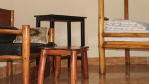A room with a wooden bed, a wooden chair, and a small wooden table. - ShoeBill Safari Lodge (Karogoto)
