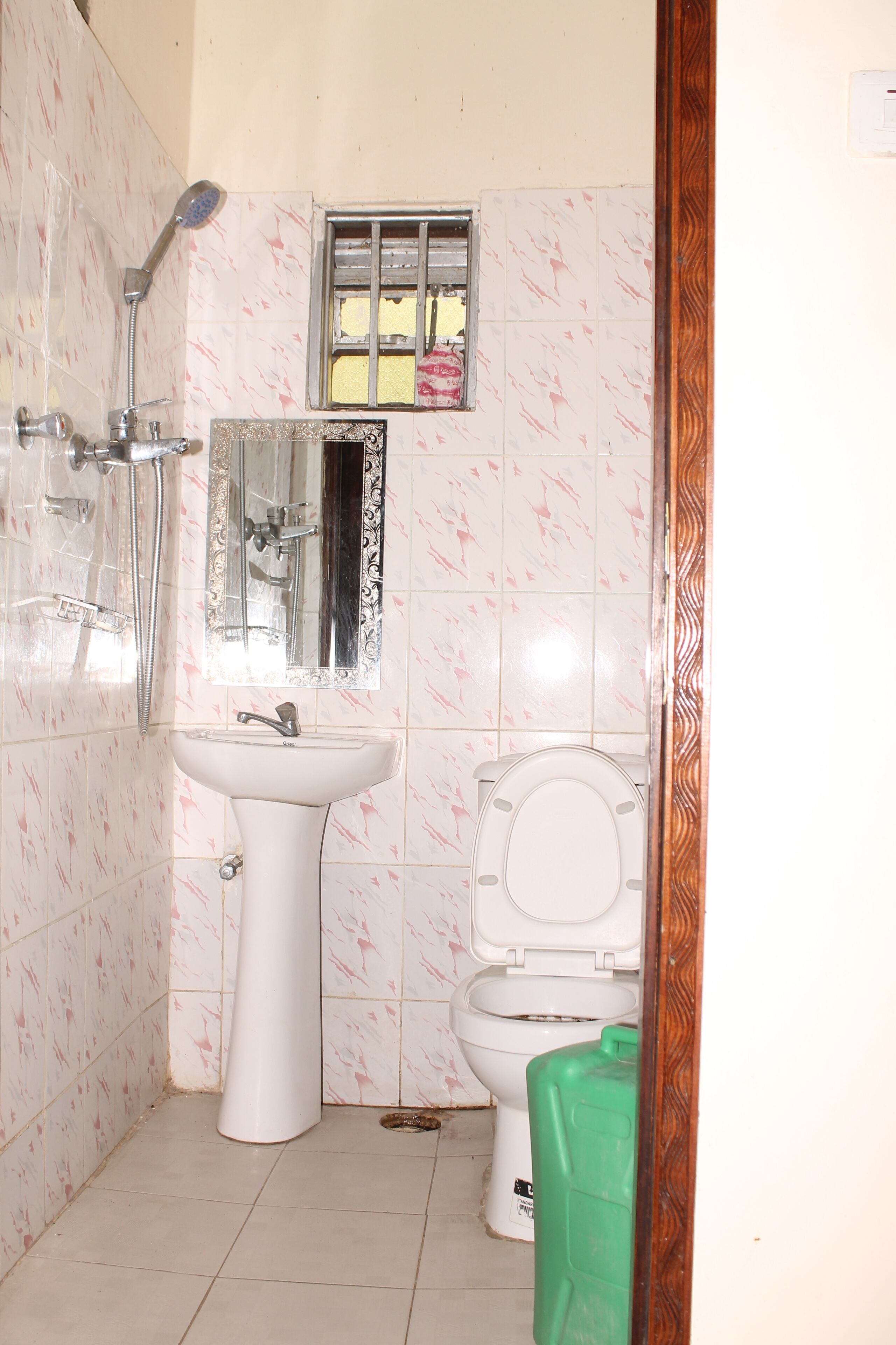 A bathroom with a sink, toilet, shower, and a small window.