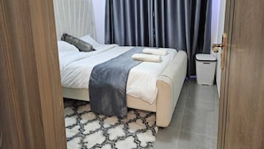 Ein ordentlich eingerichtetes Schlafzimmer mit Bett, Nachttisch und Mülleimer.