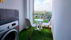 Ein kleiner Balkon mit Waschmaschine, zwei Stühlen und einem Tisch.
