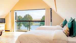 A bedroom with a large window, a bed, a TV, and a wooden floor. - Springholm Cottages (Nottingham Road)