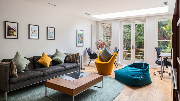 A modern living room with a sofa, coffee table, and colorful chairs.