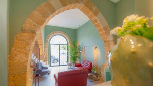 Un vestíbulo con un arco de piedra, un sofá rojo, una planta en maceta y una vista a través de un amplio arco.