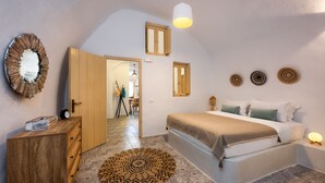Un dormitorio con cama, mesita de noche y cómoda. Hay una alfombra circular en el suelo y un espejo en la pared.