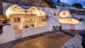 Una villa moderna con una arquitectura curva distintiva, una bicicleta estacionada afuera y un ventanal con forma de corazón.