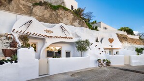 Un edificio blanco con una fachada curva distintiva, una bicicleta estacionada afuera y un adorno con forma de corazón en la pared.
