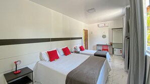 Et hotelværelse med to senge, et skrivebord, et spejl og et vindue med gardiner.