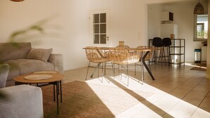 Ein modernes Wohnzimmer mit Sofa, einem Esstisch mit Stühlen und einer Küchenzeile im Hintergrund.