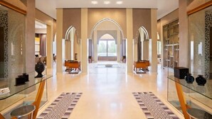 A spacious hotel lobby with a central archway, glass display cases, and a patterned floor. - Villa Mimouana Riads 18 Chambres (Marrakech)