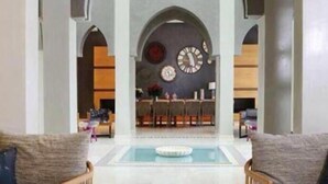 A spacious living area with a pool, a dining area with a bar, and a kitchen visible through an archway. - Villa Mimouana Riads 18 Chambres (Marrakech)