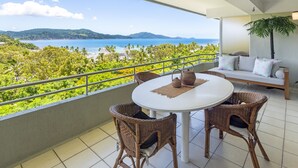 A balcony with wicker chairs, a round table, and a sofa. - Poinciana Lodge 207, Poinciana Lodge 207 on Hamilton Island (Hamilton Island)
