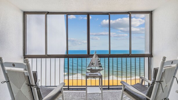 A balcony with two chairs, a small table, and a view of the ocean. - Includes Xplorie Activities and Linens. PYRAMID - Upgraded 2BR oceanfront condo w/outdoor pool. (Ocean City)