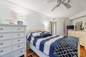 A bedroom with a bed, dresser, ceiling fan, and a television. - Includes Xplorie Activities and Linens. PYRAMID - Upgraded 2BR oceanfront condo w/outdoor pool. (Ocean City)