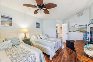 A bedroom with two beds, a ceiling fan, and artwork on the walls. - Includes Xplorie Activities and Linens. PYRAMID - Upgraded 2BR oceanfront condo w/outdoor pool. (Ocean City)