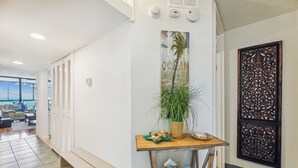 A hallway with lockers, a wooden table with a plant and decorative items, and a wall with a 'OCEAN' sign. - Includes Xplorie Activities and Linens. PYRAMID - Upgraded 2BR oceanfront condo w/outdoor pool. (Ocean City)