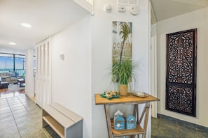 A hallway with lockers, a wooden table with a plant and decorative items, and a wall with a 'OCEAN' sign. - Includes Xplorie Activities and Linens. PYRAMID - Upgraded 2BR oceanfront condo w/outdoor pool. (Ocean City)