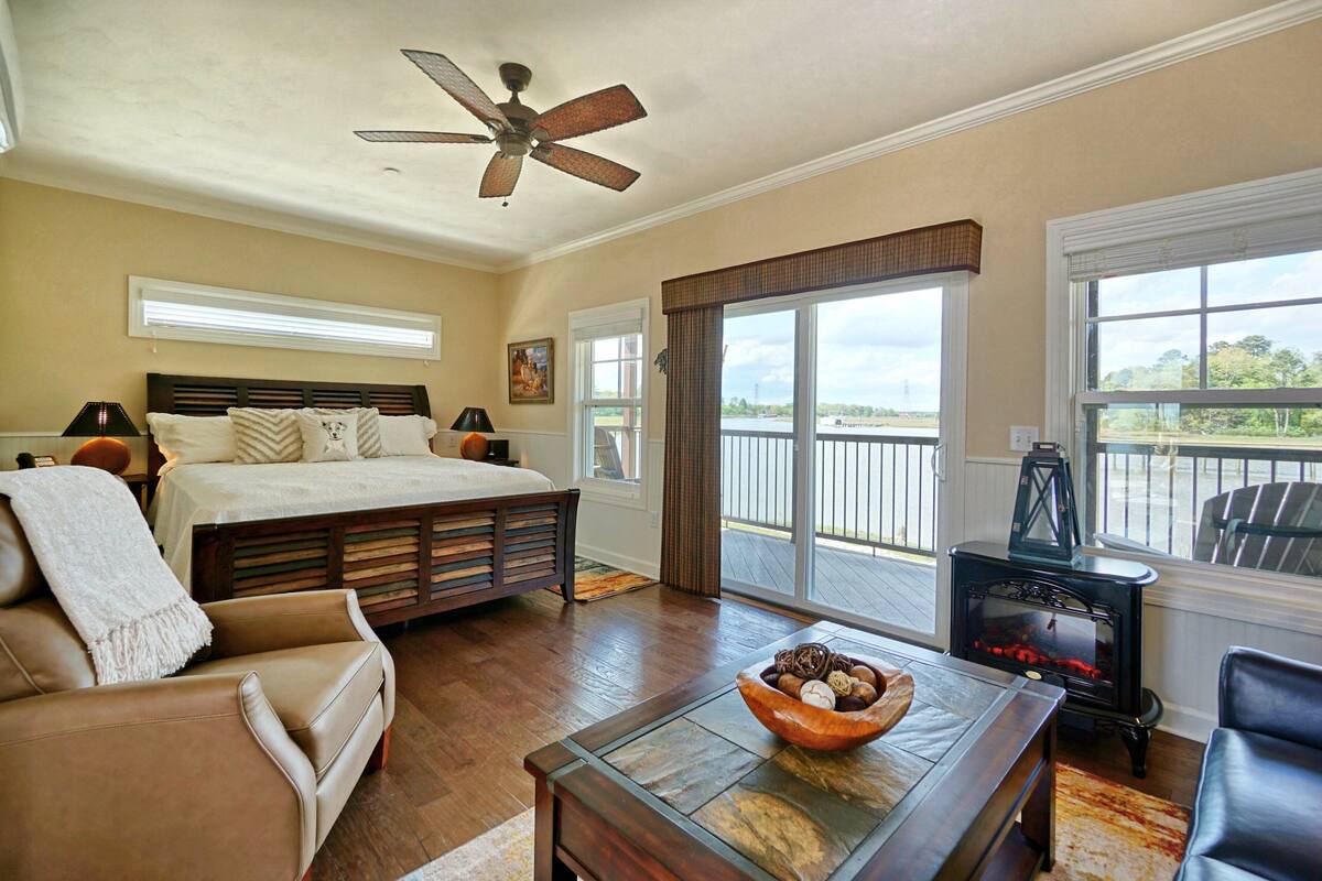 A bedroom with a large bed, a ceiling fan, and a view of the outdoors through a sliding glass door.