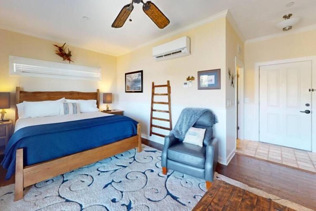 A bedroom with a bed, bedside tables, a chair, a ladder, and a door.