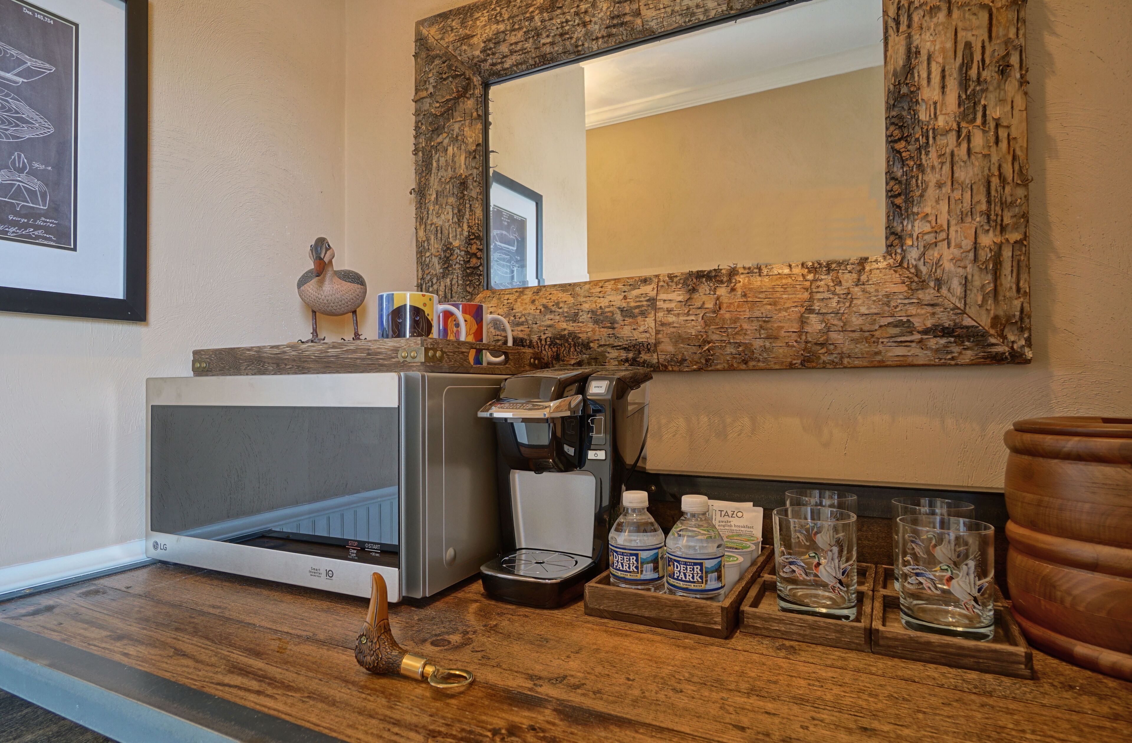 A kitchenette with a microwave, coffee maker, and a tray with water bottles and glasses.