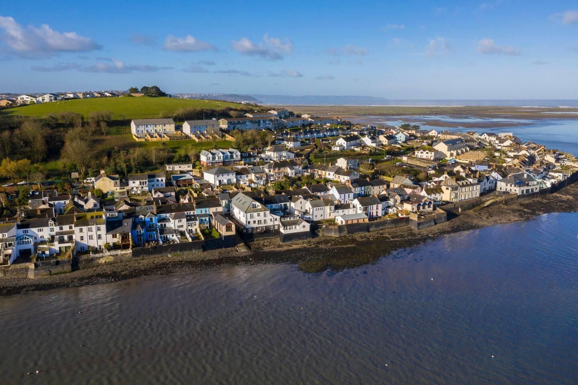 A coastal town with houses along the shoreline, a clear sky, and a view of the sea.