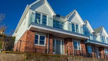 A two-story house with a brick facade, white siding, and a stone foundation.