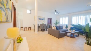 A spacious living room with a sofa, coffee table, and dining area. - 7br Massive Villa In Sosúa - 2mins From Nightlife! (Sosúa)