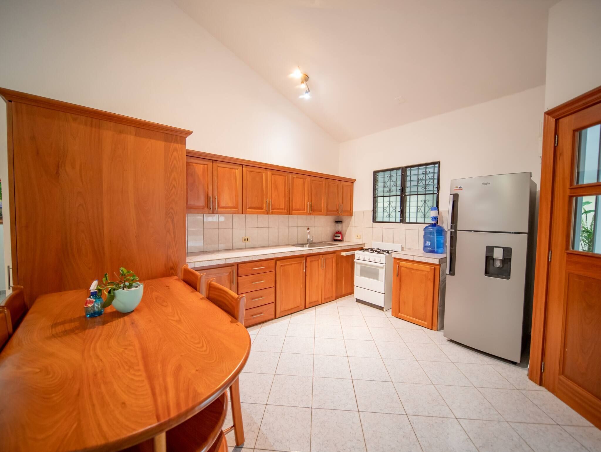 Una cocina con armarios de madera, estufa, refrigerador y una mesa de comedor con sillas.