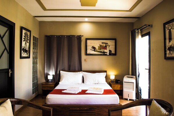 A hotel room with a large bed, two bedside tables, a heater, and artwork on the walls.
