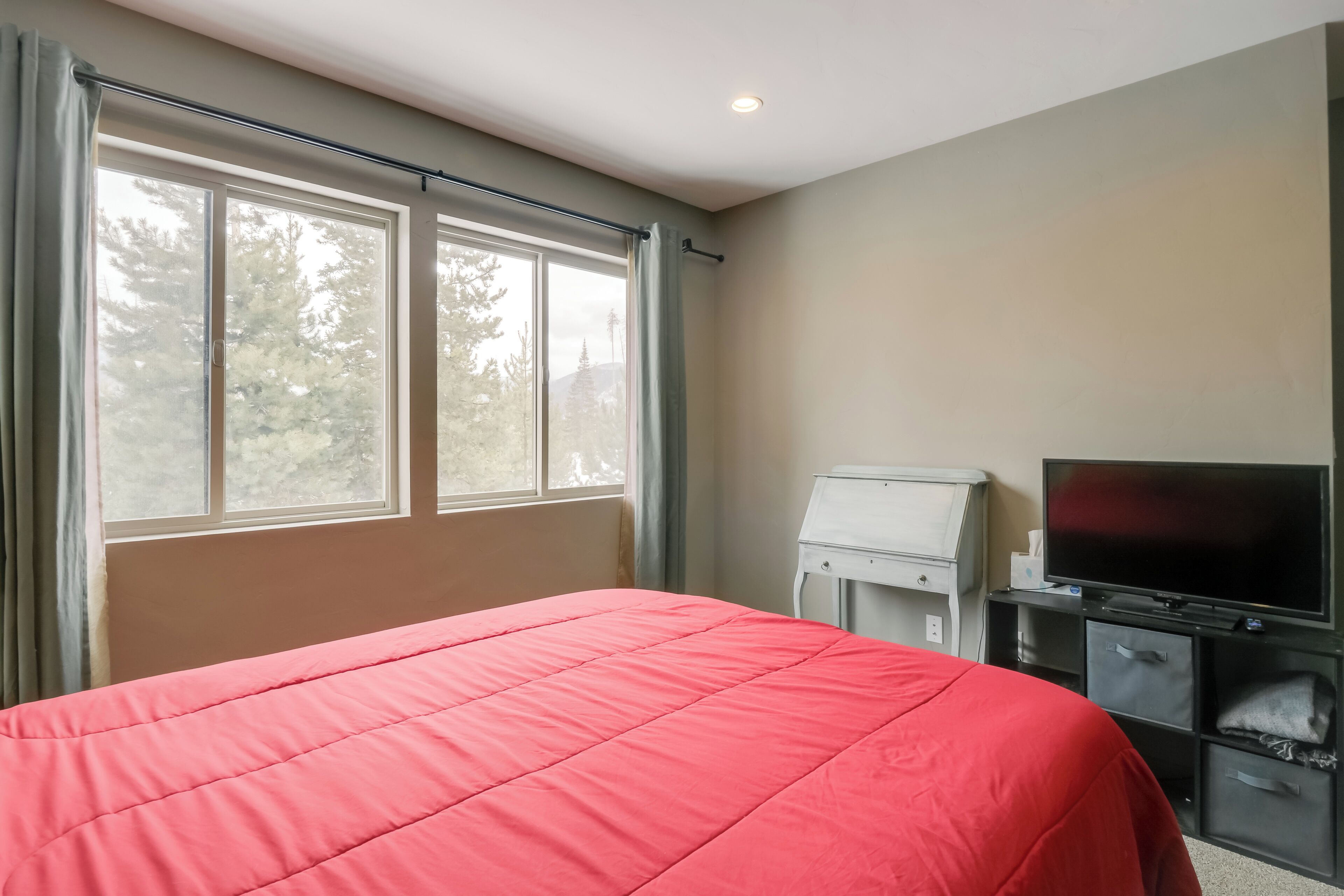 Una habitación con cama, televisión y escritorio.